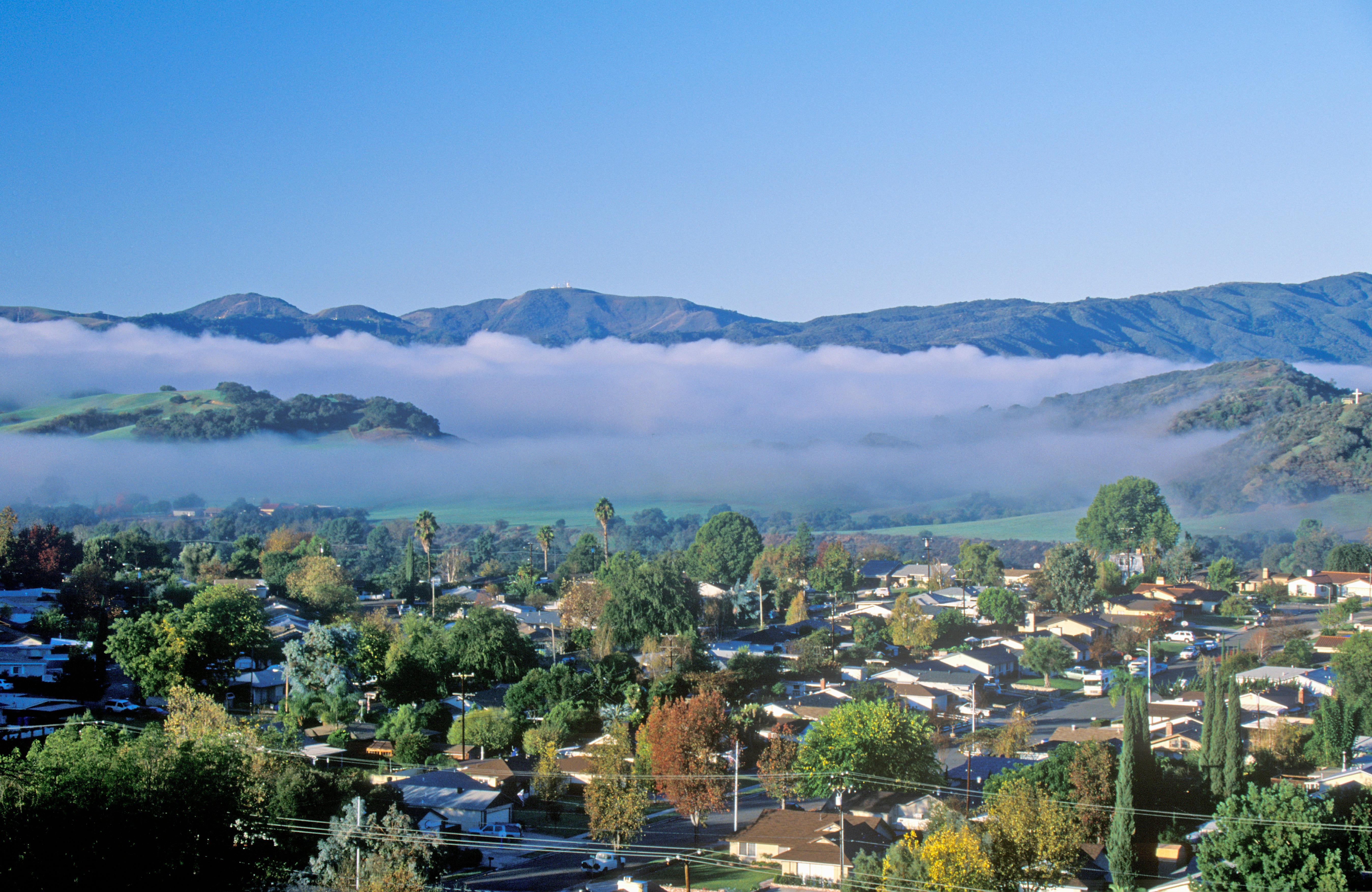 A scenic picture of Ojai California with mountains and cloud layers over a neighborhood